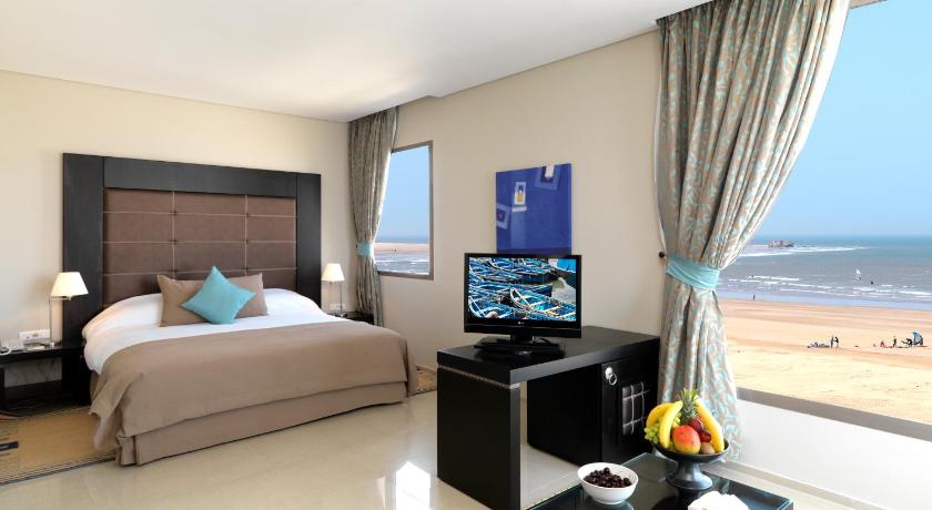 a hotel room with a large bed and a television, Atlas Essaouira & Spa in Essaouira