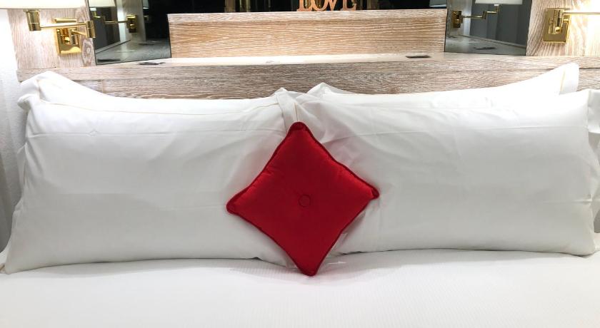 a white bed with a red pillow on top of it, Hotel Alla Posta in Saint Vincent