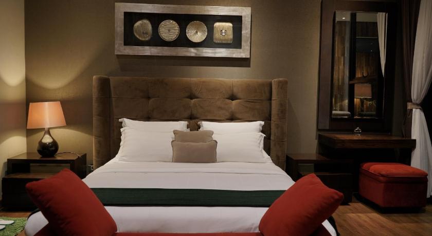 a hotel room with a bed, chair, and nightstand, D'green Villa in Bandung