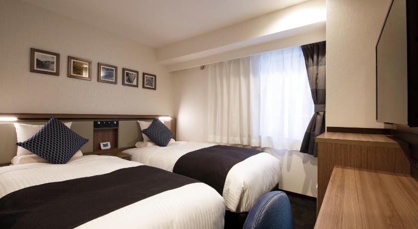 a hotel room with two beds and a television, HOTEL MYSTAYS Sapporo Susukino in Sapporo