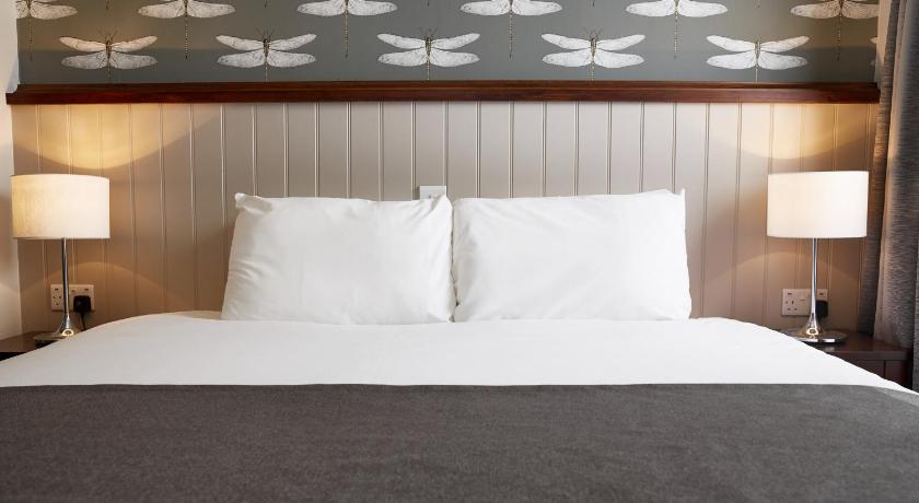 a bed with a white comforter and pillows, Sun Inn in Nottingham