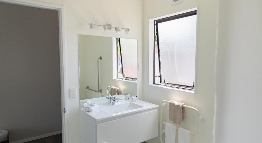 a bathroom with a sink, mirror and bath tub, BKs Palm Court Motor Lodge in Gisborne