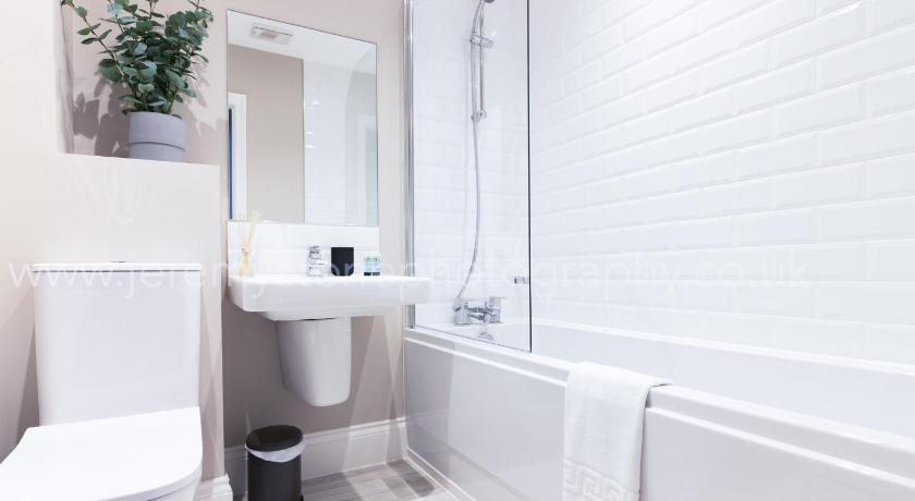 a white toilet sitting next to a bath tub in a bathroom, Moda Stays - John Brooks Serviced Houses in Birmingham