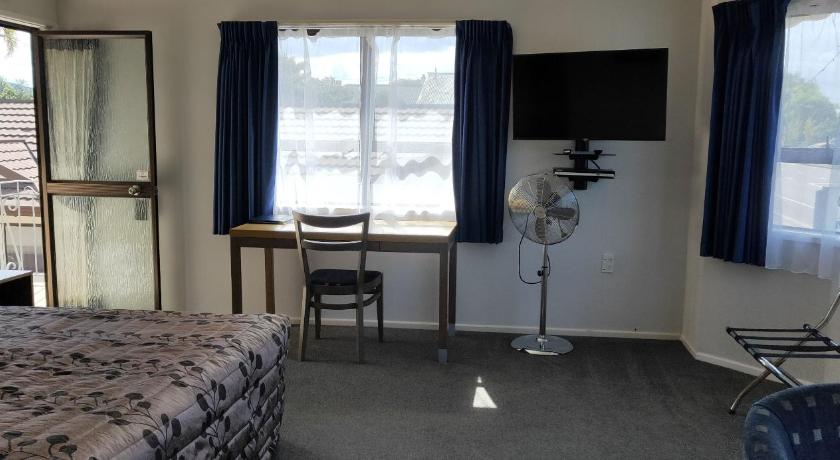 a bedroom with a bed, desk, chair and a television, Cypress Court Motel in Whangarei