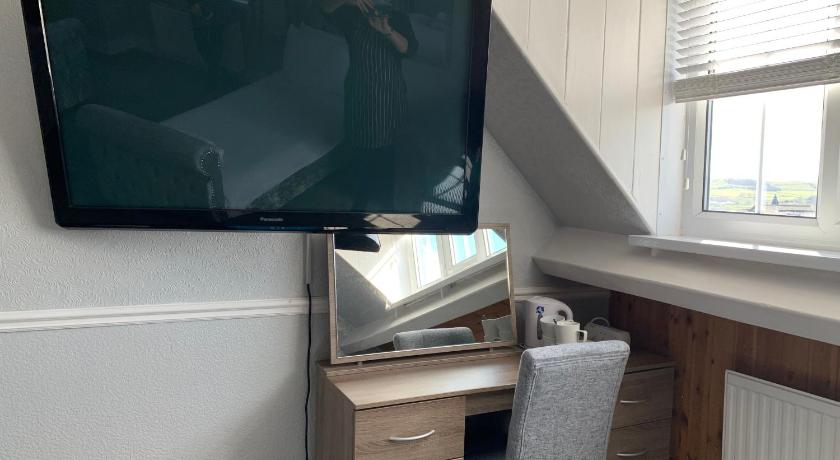 a tv sitting on top of a wooden desk next to a window, Grosvenor Hotel in Whitby