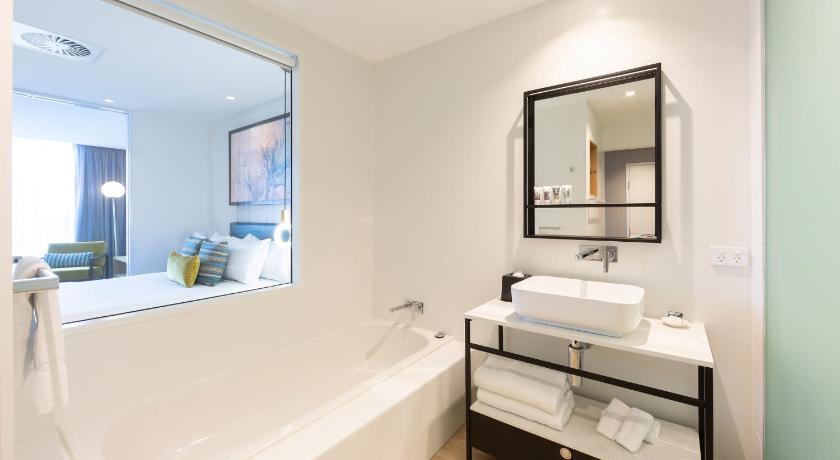 a bathroom with a tub, sink and mirror, Mercure Canberra Belconnen in Canberra