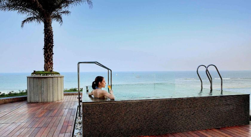 a woman sitting on a balcony overlooking a beach, Hotel Novotel Visakhapatnam Varun Beach - - An AccorHotels Brand in Visakhapatnam