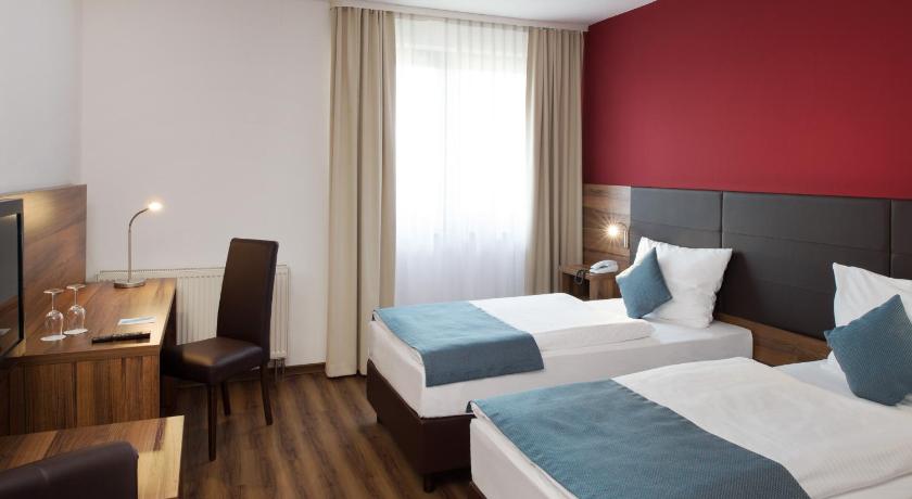 a hotel room with two beds and a television, Michel Hotel Wetzlar in Wetzlar