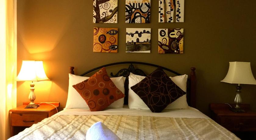 a bedroom with a bed and a lamp on the wall, Beachend Bicheno Apartment in Bicheno