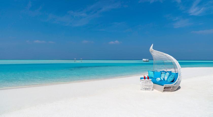 a blue and white surfboard sitting on top of a sandy beach, Anantara Dhigu Maldives Resort in Maldive Islands