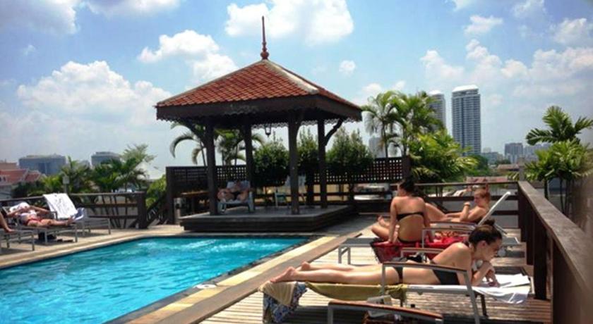 a man sitting in a chair in front of a pool, Khaosan Palace Hotel (SHA Plus+) in Bangkok