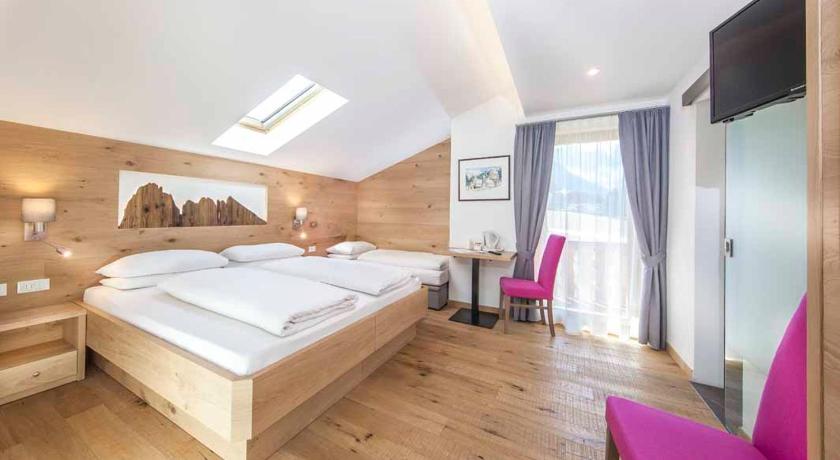 a bedroom with a bed, a dresser and a window, Hotel Garni Morene in Selva di Val Gardena