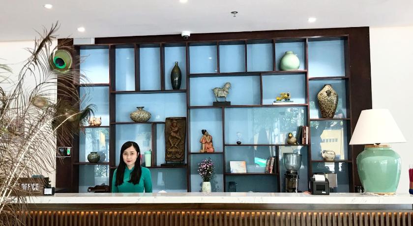 a woman is standing in front of a wall with paintings on it, Cocochine - a VIE collection in Da Nang