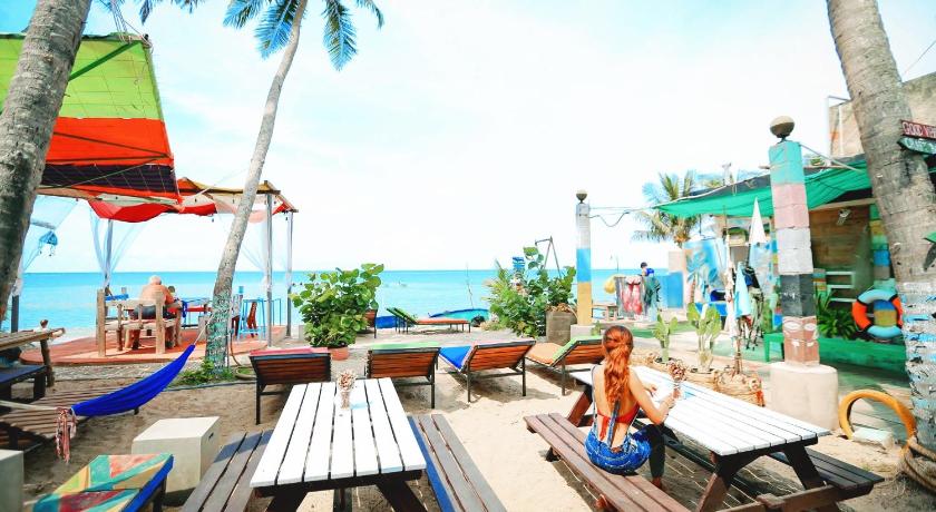 a beach area with chairs, tables and umbrellas, EVA HUT Mui Ne Beach Hostel in Phan Thiet