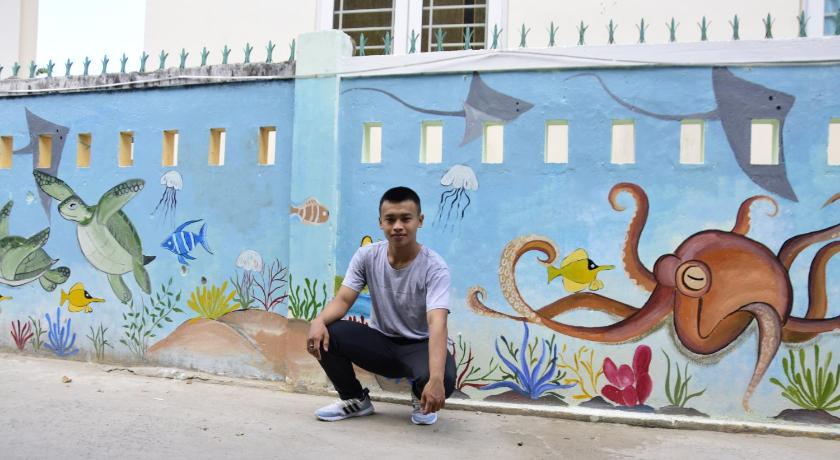 a man sitting on a sidewalk next to a graffiti covered wall, Truc Nguyen - Vinh Hy Homestay in Phan Rang – Tháp Chàm (Ninh Thuận)