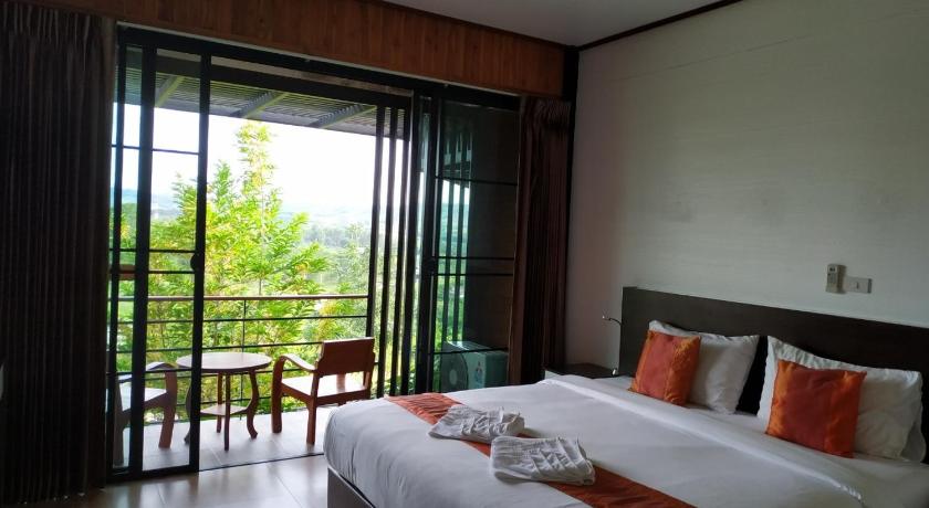 a bedroom with a large bed and a large window, Phu Khao Khor Resort in Khao Kho