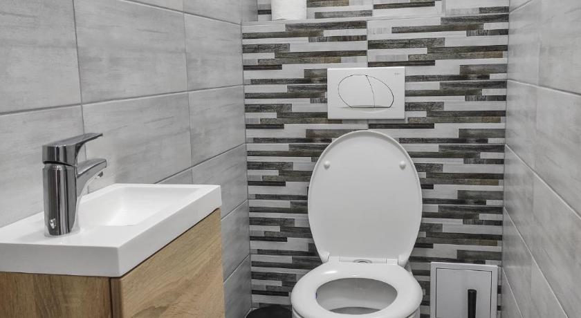 a white toilet sitting in a bathroom next to a wall, Trika Apartman in Sarvar