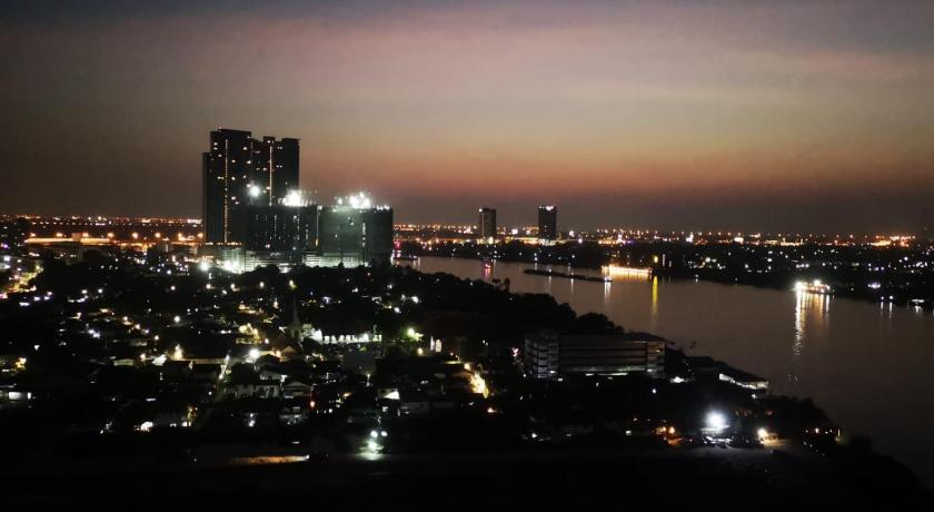 a city at night with a large body of water, river front in Nonthaburi