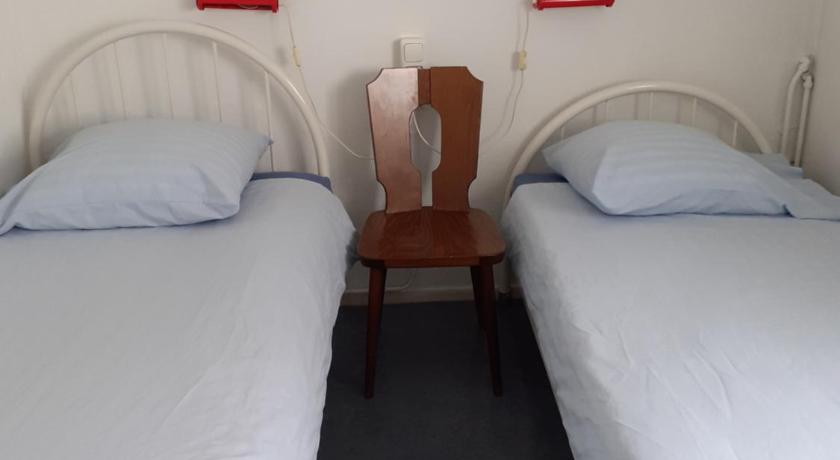 two beds in a room with two white beds, Hostel Pension Tivoli in Groningen