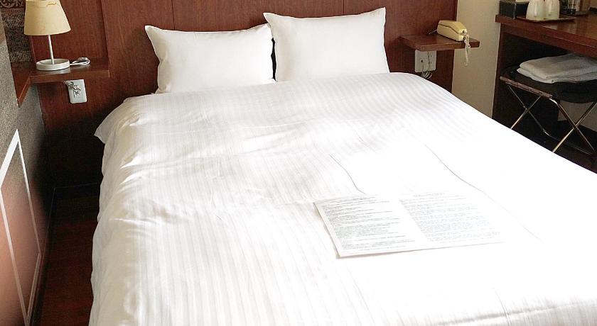 a bed with a white comforter and pillows, Sutton Hotel Hakata City in Fukuoka