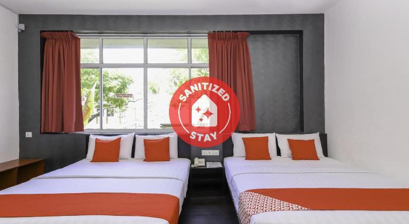 a hotel room with two beds and two windows, OYO 728 Tai Pan Hotel in Kuching