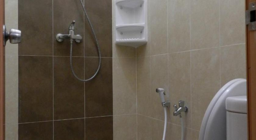 a white toilet sitting next to a shower in a bathroom, Casa Vanda Guesthouse in Tangerang