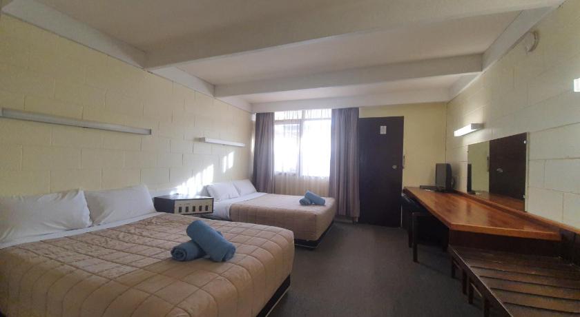 a hotel room with two beds and a desk, Charles Sturt Motor Inn in West Wyalong
