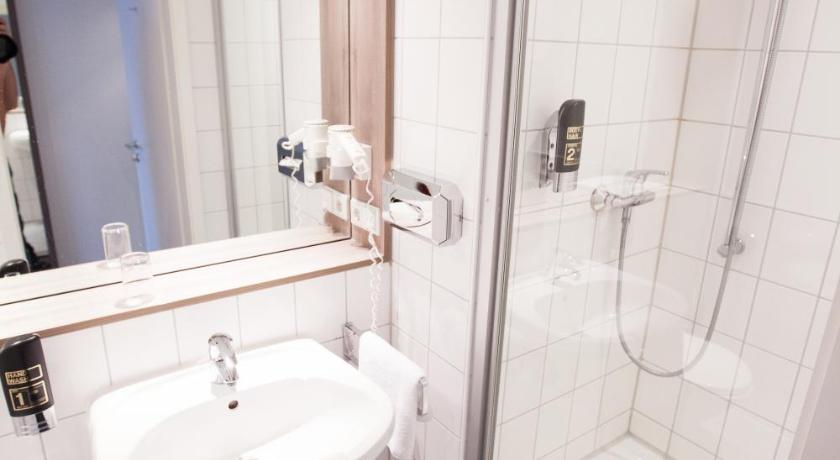 a bathroom with a shower, sink, and mirror, Manhattan Hotel in Frankfurt am Main