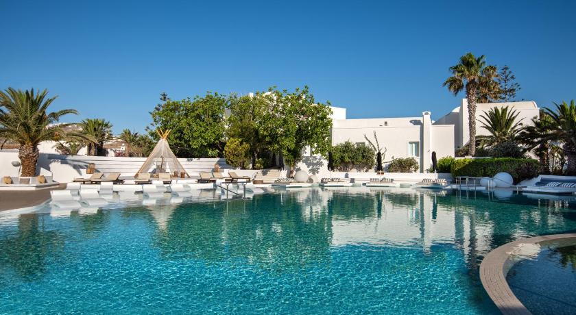 a large pool of water surrounded by palm trees, Imperial Med Resort & Spa in Santorini