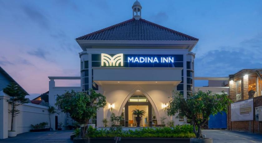 a large building with a clock on the front of it, Madina Inn in Yogyakarta