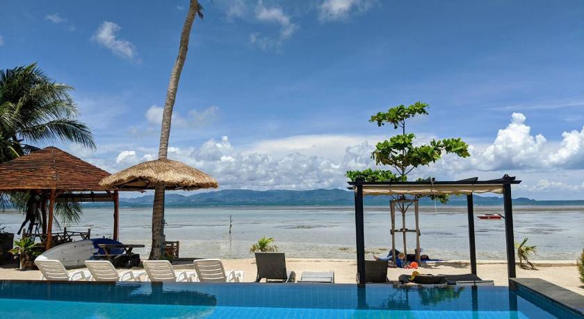 a beach area with a pool, chairs, and a beach umbrella, Samutra Residences in Ko Pha-ngan