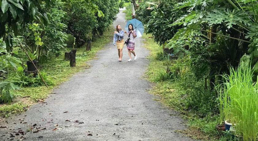 two people walking down a dirt road next to trees, Ban Suan Nai Fun Homestay in Nan