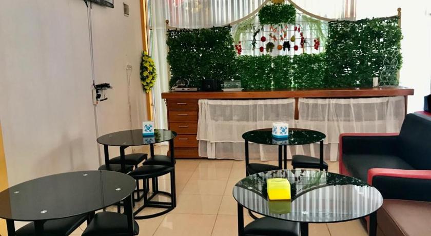 a living room filled with tables and chairs, Penginapan Intan Bandara in Sawahlunto