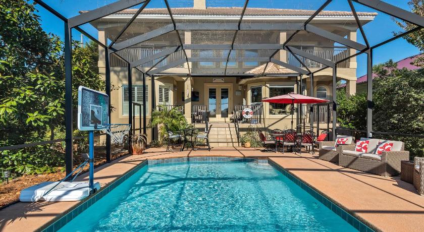 a swimming pool with a patio area with chairs and umbrellas, Casa Isla Paraiso in Destin (FL)