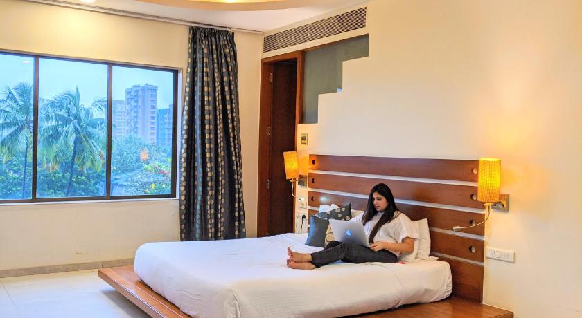 a hotel room with a bed, chair, and nightstand, Hotel Jewel of Chembur in Mumbai
