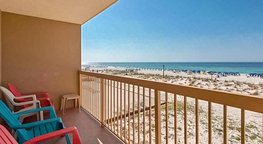 a beach area with chairs, tables, and a balcony, Pelican Beach Resort in Destin (FL)