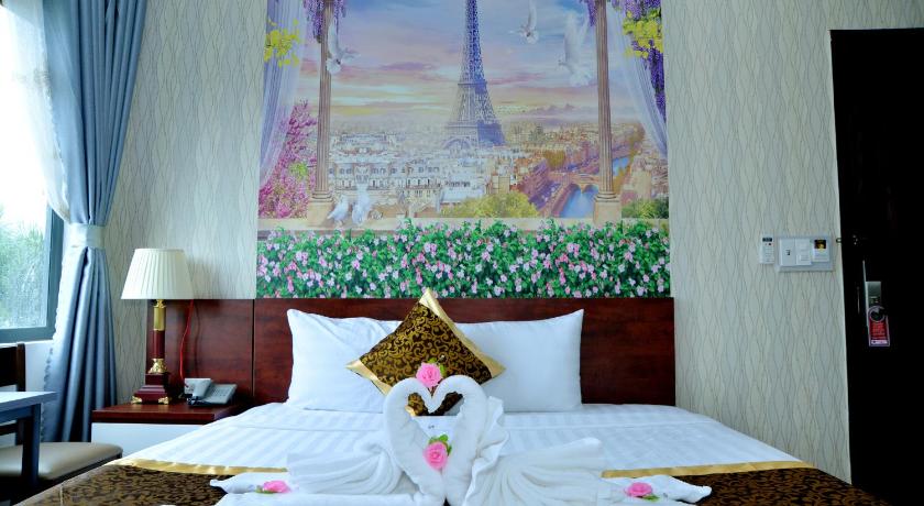 a bed with a white bedspread and flowers on it, Buon Ma Thuot Hotel in Buon Ma Thuot