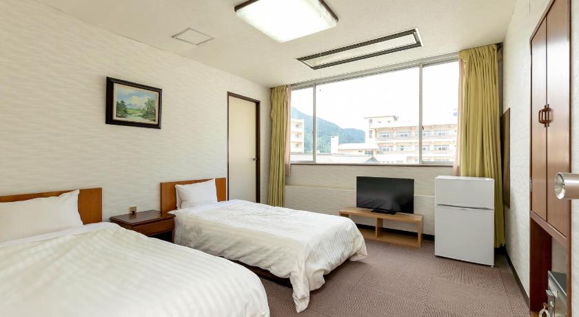 a hotel room with two beds and a television, Itoen Hotel New Sakura in Nikko