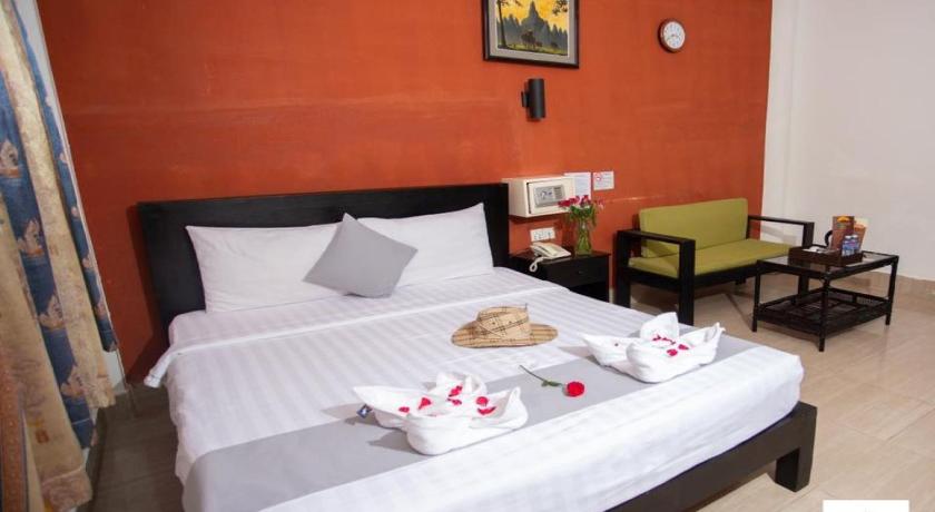 a hotel room with a bed, chair, table and lamp, Best Central Point Hotel in Phnom Penh