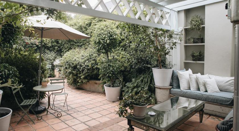 a garden area with a table, chairs, and plants, Nima Local House Hotel in Mexico City