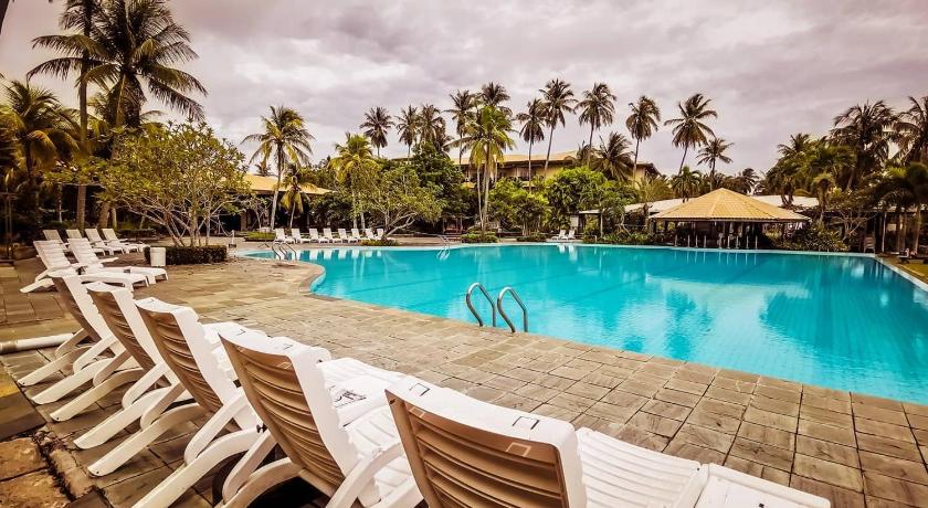 a beach with a pool, chairs, and trees, Palm Beach Resort & Spa in Labuan