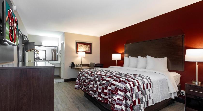 a hotel room with a bed, chair, and nightstand, Red Roof Inn Muscle Shoals in Muscle Shoals (AL)
