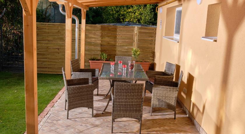 a patio area with chairs, tables and umbrellas, Kincses Sziget Apartman in Szekesfehervar