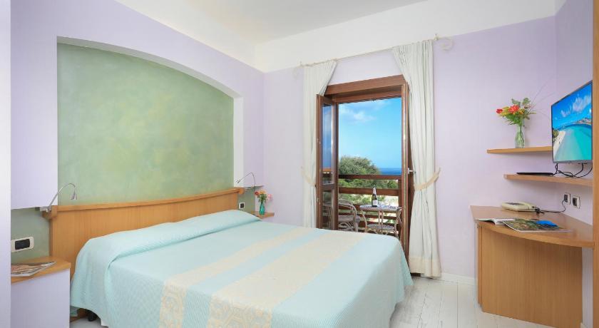 a bedroom with a bed and a desk, Hotel Cala Reale in Stintino