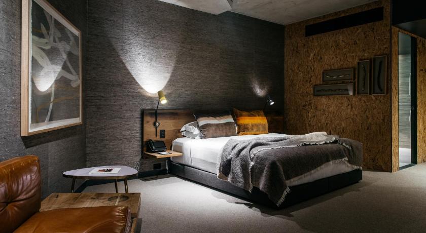 a bedroom with a bed, chair and a lamp, Ovolo Nishi in Canberra