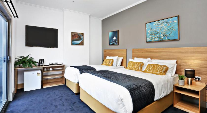 a hotel room with a bed, desk, and television, Meridian Hotel Hurstville in Sydney