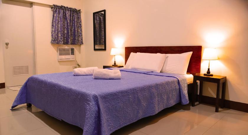 a bed room with a white bedspread and a blue comforter, CounTess Pension House in Cebu