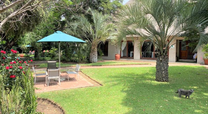 a garden area with a lawn and a patio, Safari Club SA in Johannesburg
