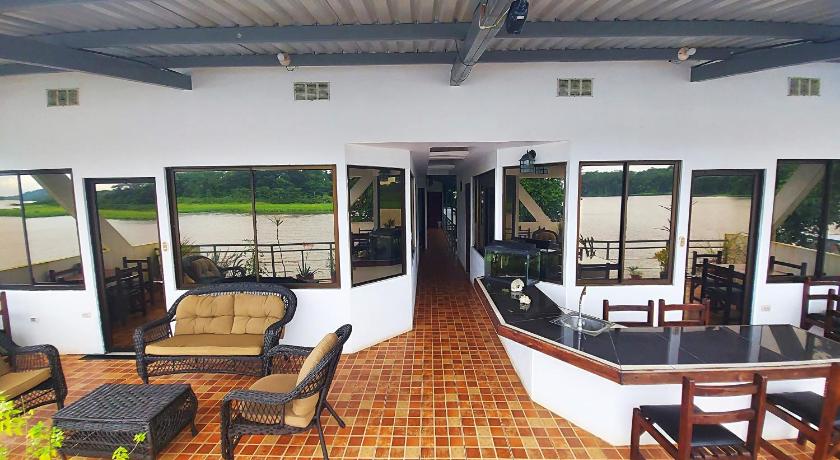 a patio area with chairs, tables, chairs and umbrellas, Tortuguero Adventures GuestHouse in Tortuguero