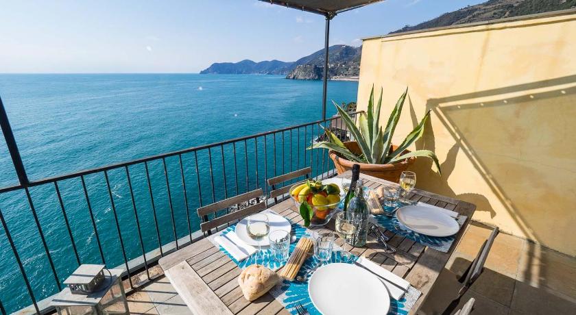 a dining room table with a balcony overlooking the ocean, La Lampara Sea View Terrace Apartment in Riomaggiore